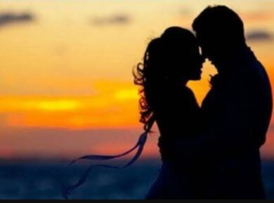 Zakochana para obejmująca się o zachodzie słońca, sylwetki na tle pomarańczowego nieba nad morzem.